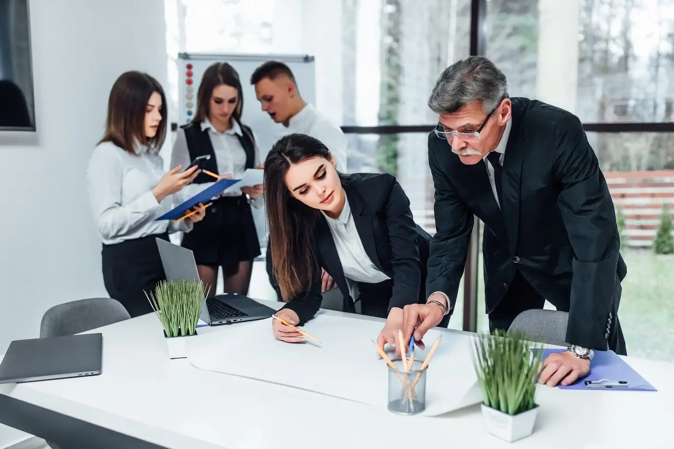 Jóvenes profesionales del mundo de los negocios pintando y escribiendo en un espacio de oficina moderno.